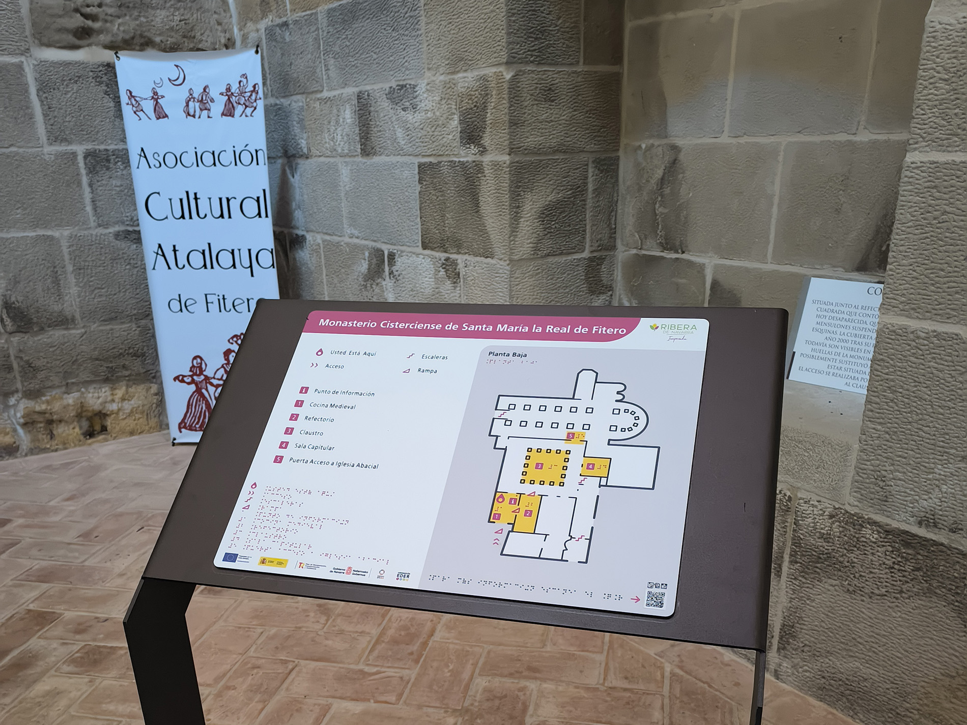 Un panel informativo con el plano háptico del Monasterio Cisterciense de Santa María la Real de Fitero se encuentra sobre un soporte metálico.